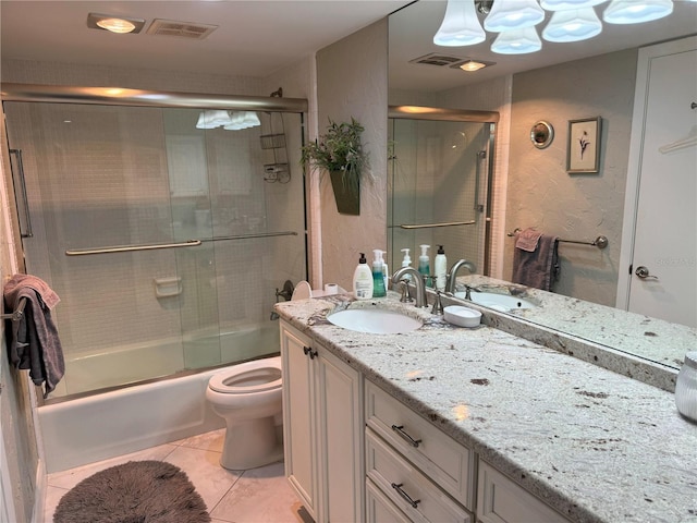bathroom with vanity, enclosed tub / shower combo, tile patterned floors, toilet, and a textured wall