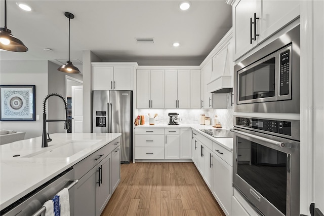 16226 Hidden Oak Loop, Bradenton, FL 34211 - kitchen featuring stainless steel appliances, a sink, decorative light fixtures, light wood-style flooring, and white cabinetry