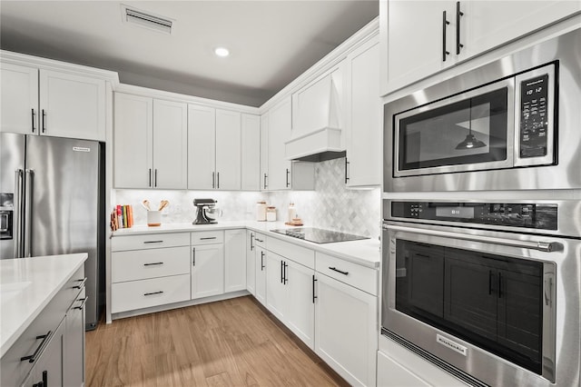 16226 Hidden Oak Loop, Bradenton, FL 34211 - kitchen with stainless steel appliances, light countertops, custom exhaust hood, white cabinetry, and recessed lighting