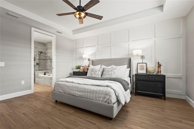 16226 Hidden Oak Loop, Bradenton, FL 34211 - bedroom featuring wood finished floors, baseboards, a tray ceiling, and ensuite bath
