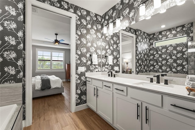 16226 Hidden Oak Loop, Bradenton, FL 34211 - ensuite bathroom with double vanity, wallpapered walls, ceiling fan, wood finished floors, and baseboards