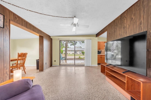 6628 Auburn Ave, Bradenton, FL 34207 - living area with dark speckled floor, a textured ceiling, ceiling fan, wooden walls, and lofted ceiling
