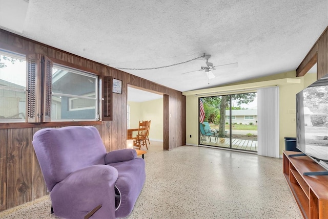 6628 Auburn Ave, Bradenton, FL 34207 - living area featuring speckle patterned floor, ceiling fan, wooden walls, and a textured ceiling