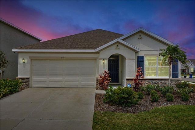 view of front of house featuring stone siding, stucco siding, concrete driveway, and a garage