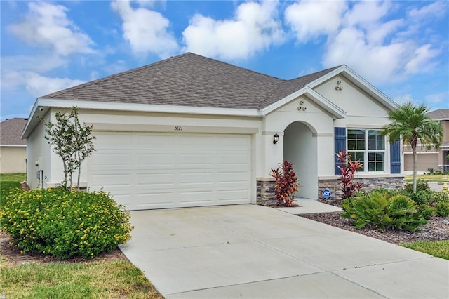 single story home with concrete driveway, a garage, stone siding, stucco siding, and a shingled roof