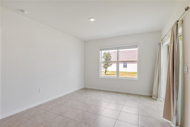 empty room with a smoke detector, light tile patterned floors, and baseboards