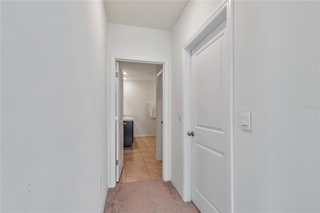 hallway with light tile patterned floors, light colored carpet, and baseboards