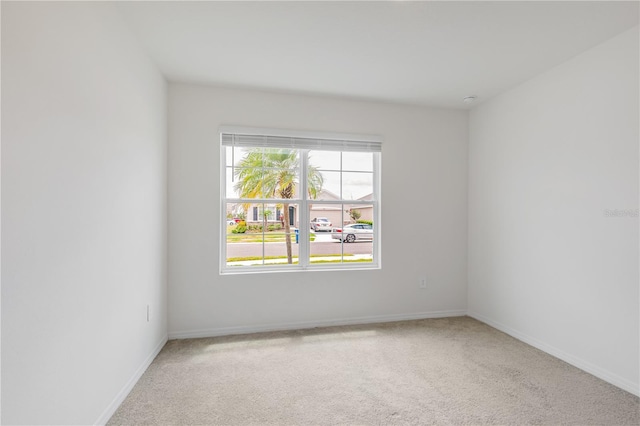 empty room featuring light carpet and baseboards