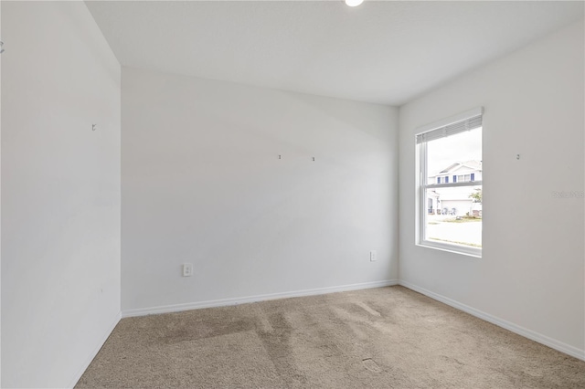 empty room featuring light colored carpet and baseboards