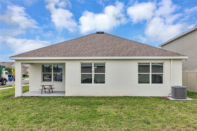back of house featuring a shingled roof, cooling unit, a patio area, and a lawn