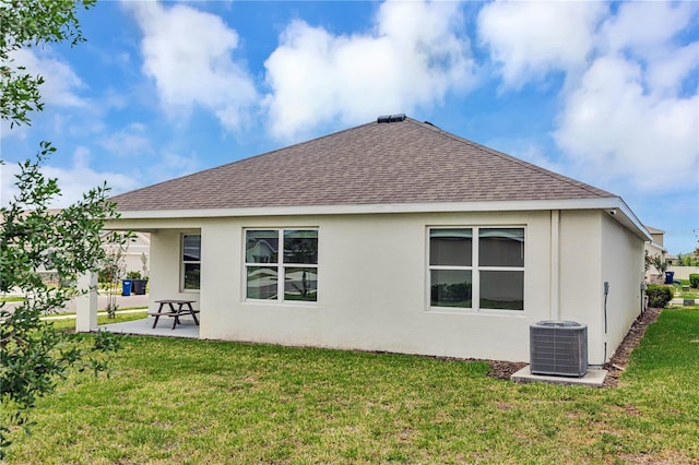 back of house with roof with shingles, cooling unit, a patio area, stucco siding, and a yard