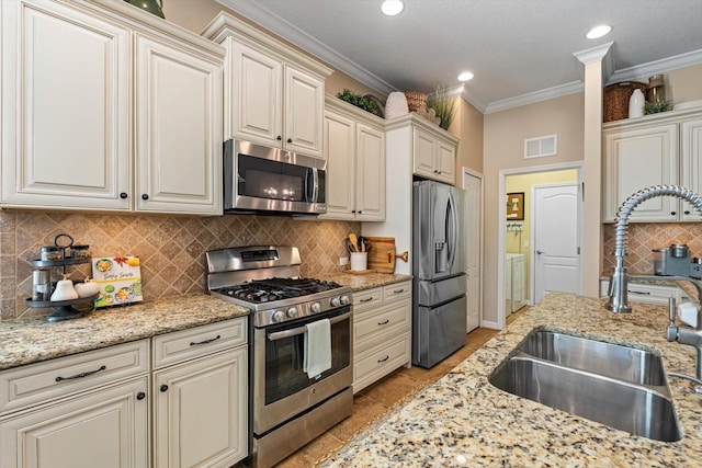 11508 Griffith Park Ter, Bradenton, FL 34211 - kitchen with stainless steel appliances, a sink, washer and clothes dryer, decorative backsplash, and crown molding