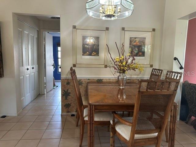 2181 Pine Gardens Trl, Sarasota, FL 34231 - dining room featuring a chandelier, light tile patterned flooring, and baseboards