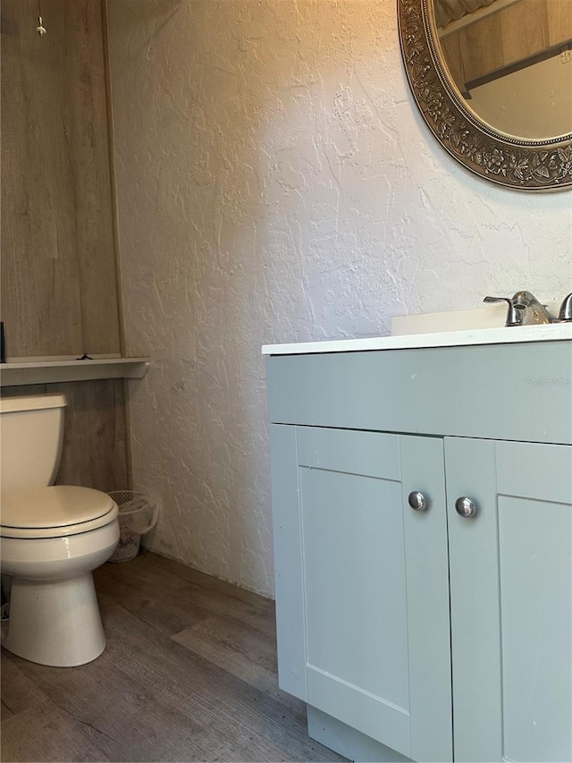 2181 Pine Gardens Trl, Sarasota, FL 34231 - bathroom featuring a textured wall, toilet, vanity, and wood finished floors