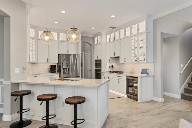 6470 Indigo Bunting Pl, Lakewood Ranch, FL 34202 - kitchen with appliances with stainless steel finishes, wine cooler, crown molding, a breakfast bar, and decorative backsplash