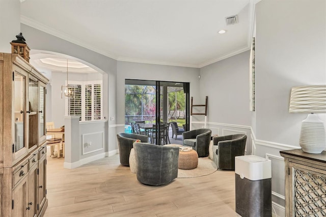 6470 Indigo Bunting Pl, Lakewood Ranch, FL 34202 - living area with light wood-style floors, wainscoting, crown molding, arched walkways, and a chandelier