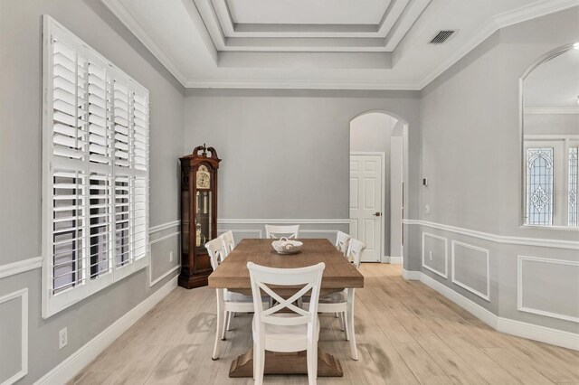 6470 Indigo Bunting Pl, Lakewood Ranch, FL 34202 - dining room featuring arched walkways, light wood finished floors, a raised ceiling, crown molding, and wainscoting