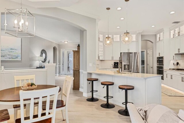 6470 Indigo Bunting Pl, Lakewood Ranch, FL 34202 - kitchen with stainless steel refrigerator with ice dispenser, arched walkways, a kitchen breakfast bar, crown molding, and stovetop