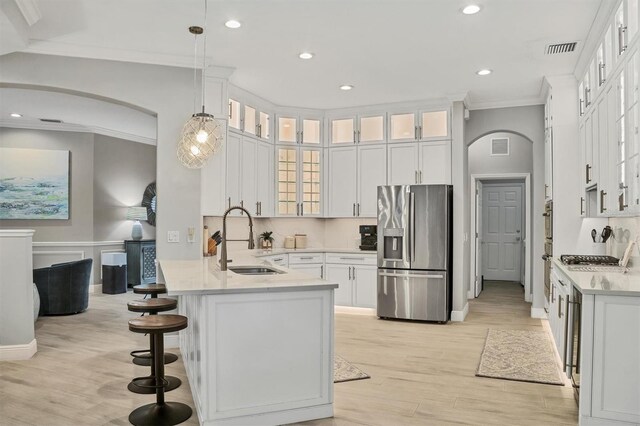 6470 Indigo Bunting Pl, Lakewood Ranch, FL 34202 - kitchen with stainless steel appliances, arched walkways, a peninsula, crown molding, and a kitchen breakfast bar