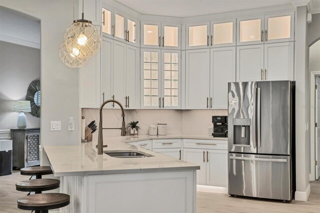 6470 Indigo Bunting Pl, Lakewood Ranch, FL 34202 - kitchen featuring stainless steel fridge, light stone counters, a kitchen bar, white cabinets, and a peninsula
