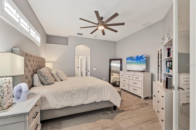6470 Indigo Bunting Pl, Lakewood Ranch, FL 34202 - bedroom with arched walkways, light wood-style flooring, multiple windows, and a ceiling fan