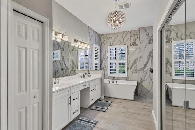 6470 Indigo Bunting Pl, Lakewood Ranch, FL 34202 - full bathroom featuring double vanity, a chandelier, tile walls, a closet, and a soaking tub