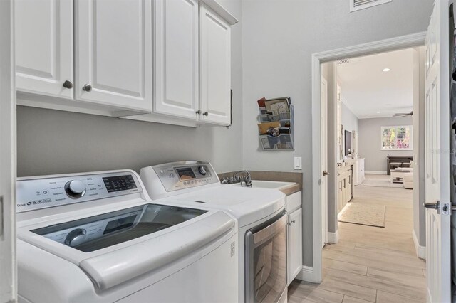6470 Indigo Bunting Pl, Lakewood Ranch, FL 34202 - laundry room featuring washer and dryer, cabinet space, and light wood-style floors