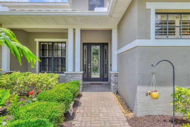 6470 Indigo Bunting Pl, Lakewood Ranch, FL 34202 - doorway to property with stucco siding, stone siding, and a porch