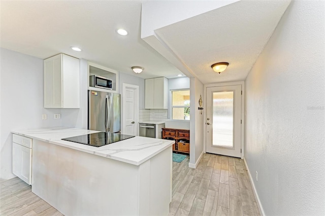 9409 Catalina Dr, Bradenton, FL 34210 - kitchen featuring appliances with stainless steel finishes, white cabinetry, and a peninsula