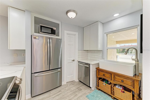 9409 Catalina Dr, Bradenton, FL 34210 - kitchen with stainless steel appliances, a sink, light wood finished floors, light stone counters, and white cabinetry