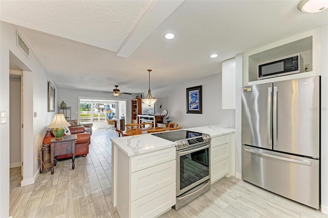 9409 Catalina Dr, Bradenton, FL 34210 - kitchen with appliances with stainless steel finishes, a peninsula, light wood-type flooring, white cabinets, and recessed lighting