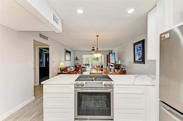 9409 Catalina Dr, Bradenton, FL 34210 - kitchen featuring appliances with stainless steel finishes, open floor plan, light wood finished floors, a peninsula, and white cabinetry