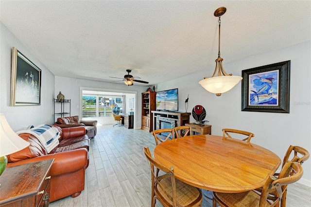 9409 Catalina Dr, Bradenton, FL 34210 - dining space featuring light wood finished floors, a ceiling fan, baseboards, and a glass covered fireplace