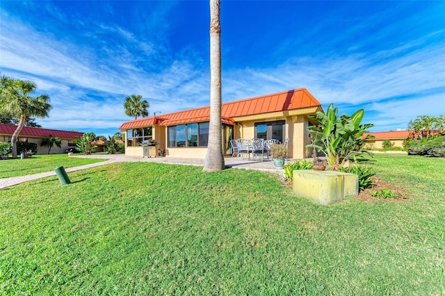 9409 Catalina Dr, Bradenton, FL 34210 - back of house featuring metal roof, a standing seam roof, a patio area, and a lawn