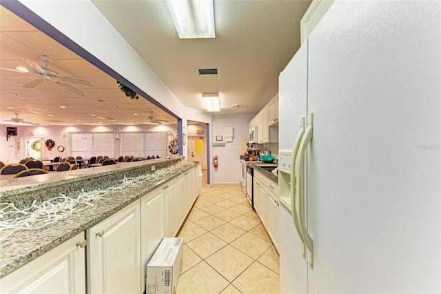 9409 Catalina Dr, Bradenton, FL 34210 - kitchen featuring white fridge with ice dispenser, light tile patterned flooring, light stone counters, ceiling fan, and open floor plan