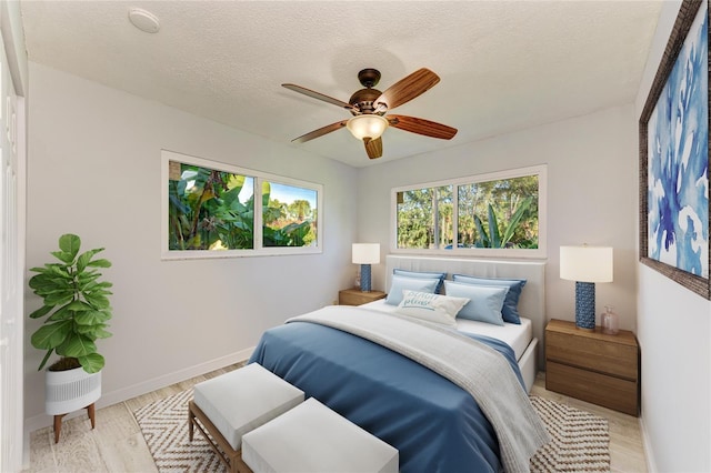 9409 Catalina Dr, Bradenton, FL 34210 - bedroom featuring baseboards, light wood-style flooring, a textured ceiling, and a ceiling fan