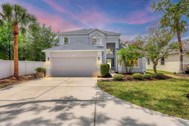 traditional home featuring stucco siding, an attached garage, concrete driveway, and roof with shingles