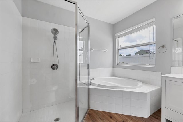 bathroom with a shower stall, wood finished floors, vanity, and a garden tub
