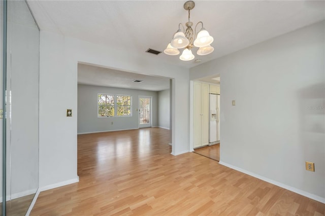 unfurnished dining area featuring a chandelier, light wood-style floors, and baseboards