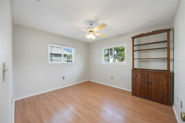 unfurnished room with light wood-style floors, a ceiling fan, and baseboards