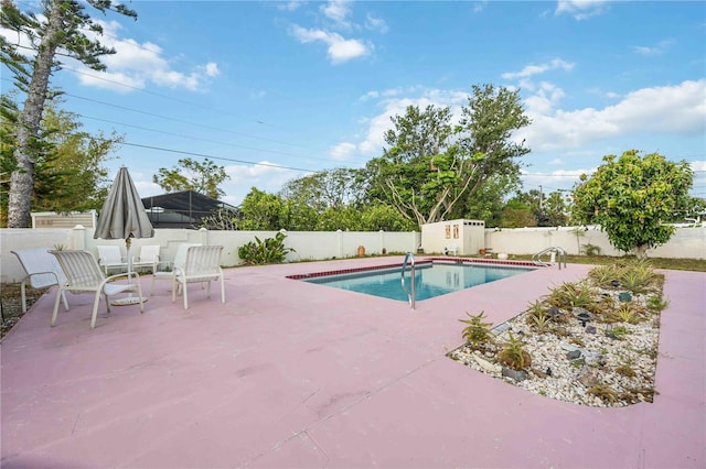 view of pool featuring a storage shed, a patio, a fenced backyard, and an outbuilding