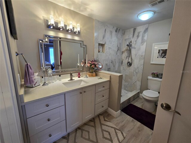 bathroom featuring toilet, a walk in shower, and vanity