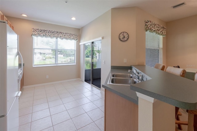 4103 Foristall Ave Unit 4103, Sarasota, FL 34233 - kitchen with freestanding refrigerator, a sink, a kitchen breakfast bar, a peninsula, and dark countertops