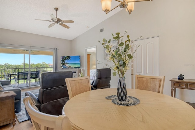 dining space featuring ceiling fan, light wood finished floors, and high vaulted ceiling