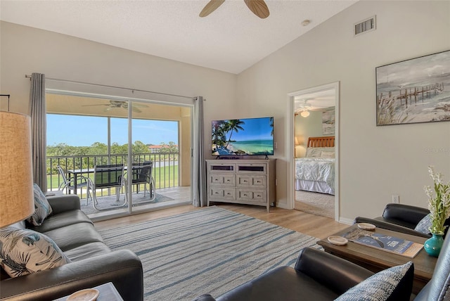 living room featuring a ceiling fan, vaulted ceiling, wood finished floors, and a textured ceiling