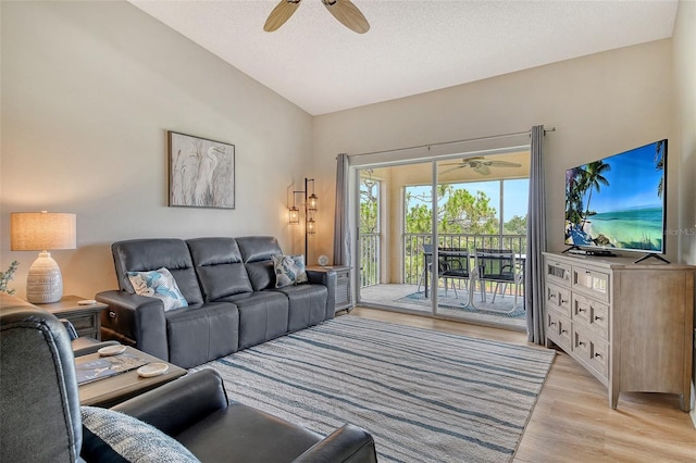 living area with ceiling fan, lofted ceiling, light wood finished floors, and a textured ceiling