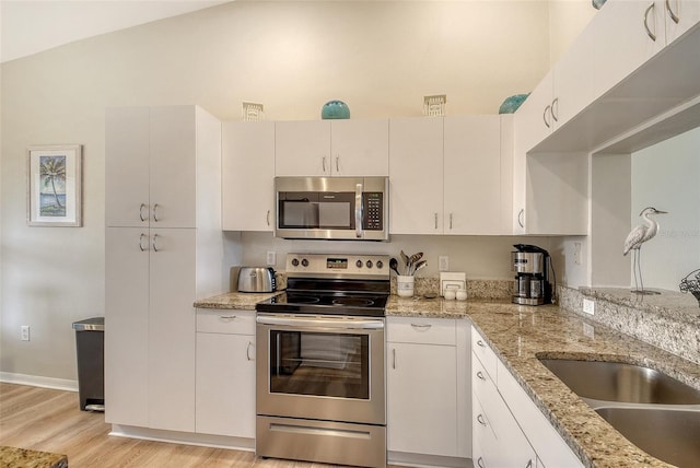 kitchen featuring appliances with stainless steel finishes, light wood-style floors, a sink, and light stone countertops