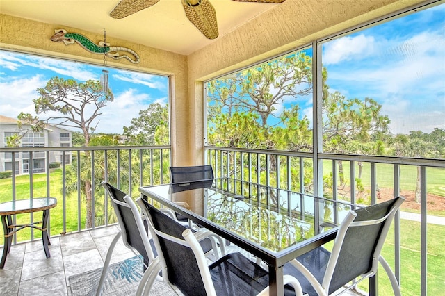 sunroom / solarium with ceiling fan, outdoor dining space, stone finish floors, and a textured wall