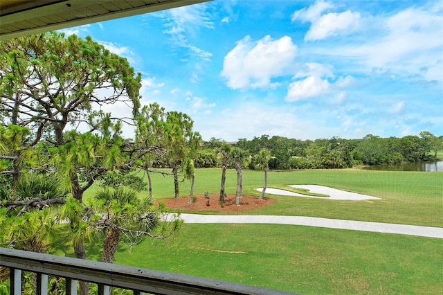 view of home's community with a lawn, view of wooded area, golf course view, and a water view