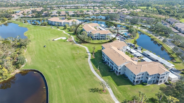 drone / aerial view of a nearby body of water, a golf course, and apartment complex
